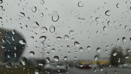 Raindrops on wet glass overlooking the street. City landscape blurred by water