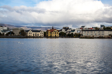 Fototapeta na wymiar LAKE TJÖRNIN, REYKJAVIK, ICELAND - SEPTEMBER 18, 2018: View of lake Tjörnin and cityscape with buildings and houses.