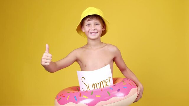 Cute little boy with inflatable ring showing thumb-up on color background