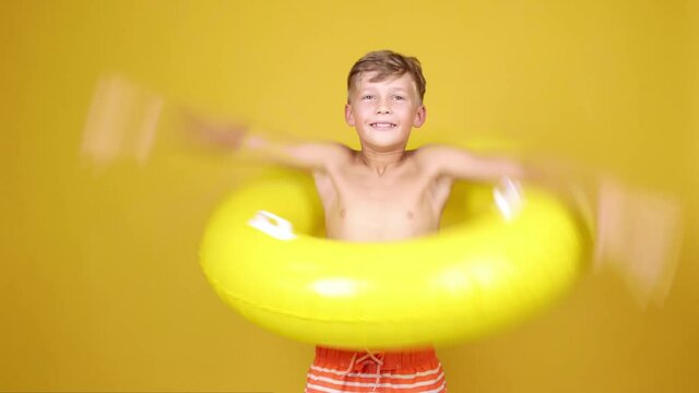 Cute little boy catching inflatable ring and showing thumb-up against color background