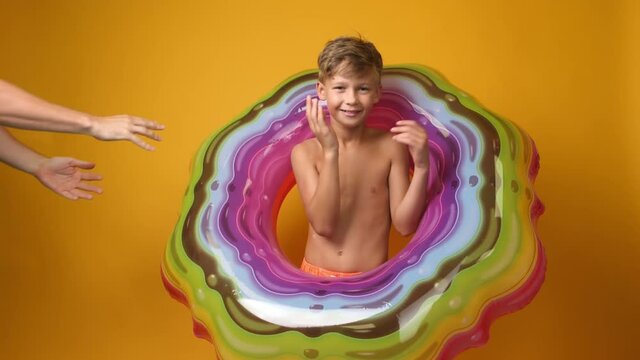 Cute little boy with different inflatable rings on color background