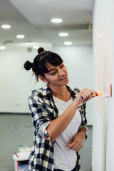Beautiful girl painting the wall with a roller. Interior renovation