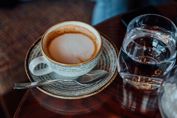 Beautiful businesswoman with red hair talking on a mobile phone and drinking a coffee while working on a tablet.