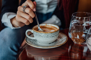 Beautiful businesswoman with red hair talking on a mobile phone and drinking a coffee while working on a tablet.