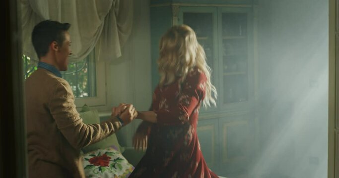 Cinematic shot of young carefree happy smiling homosexual female gay and transgender man couple in love is enjoying time together and having fun to dance together while listening to the music at home