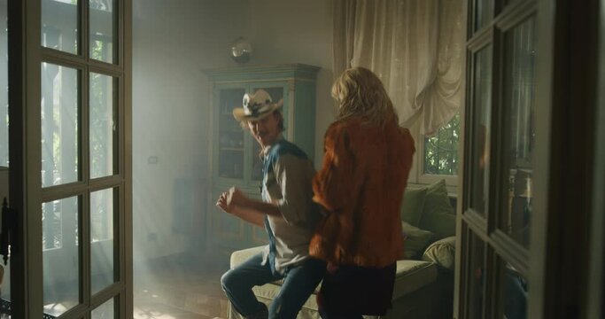 Cinematic shot of young carefree happy smiling homosexual male gay and transgender woman couple in love is enjoying time together and having fun to dance together while listening to the music at home