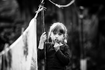 Funny girl with clothespin and the clothesline. Black and white photography.