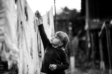 Little five-year girl with clothespin outdoor. Black and white photo.