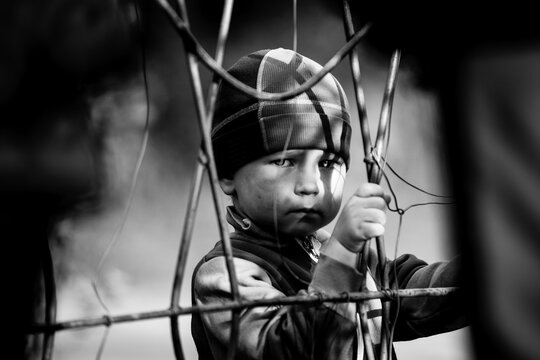 An aggrieved little boy, with a sad look in his eyes. Black and white photography.