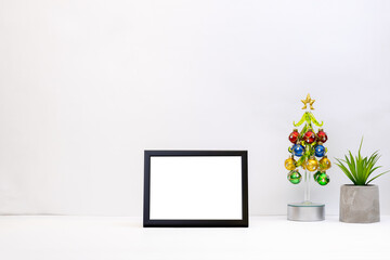 office or home workplace mockup. template christmas greeting card. white table top with blank frame on it. stationery and christmas decorations at desktop. side view