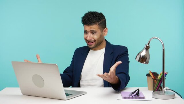 Unhappy shocked man shouting and screaming holding hand on head, cant understand what happened with laptop, frustrated with information lost. Indoor studio shot isolated on blue background