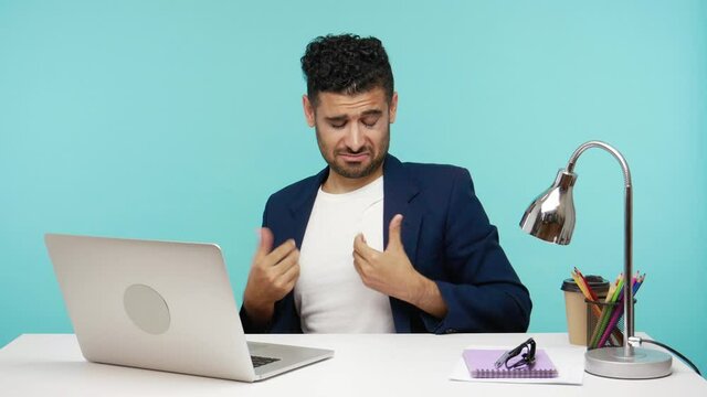 Self confident egoistic man pointing fingers on himself, proud of his achievements, bragging success looking at laptop display. Indoor studio shot isolated on blue background
