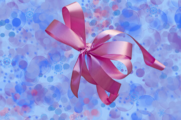 Bright pink ribbon on an abstract blue and white blurred background with stars, snowflakes, bokeh