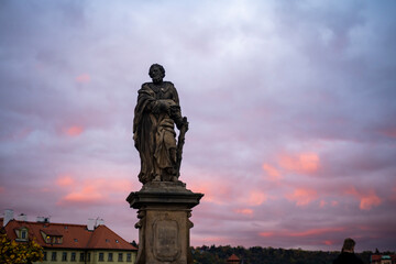 Obraz premium statue on Charles bridge from 24 century and in the background colorful sky at sunset