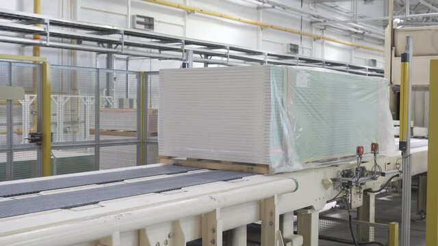Packing drywall sheets on a conveyor. Plasterboard plant. Factory or workshop manufacture of drywall, plasterboard sheets. Gypsum board conveyor.