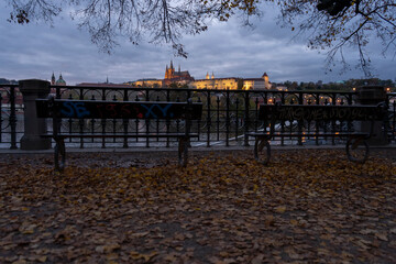 
railings and sidewalk for pedestrians and street lights and in the background Prague Castle and St. Vitus Cathedral at night in the center of Prague