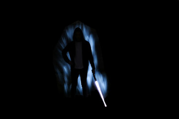 Silhouette of a man with a light saber. Lightpainting scene. Boy with light fiber optic and leds in...