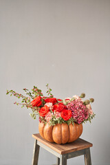 Flowers arrangement in pumpkin on wooden table. Fresh cut flowers for decoration home. European...