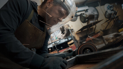 A man in gloves cuts metal with a circular saw, a lot of sparks. The working process