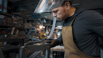 Obraz na płótnie Canvas A blacksmith forges a metal piece with an unusual hammer