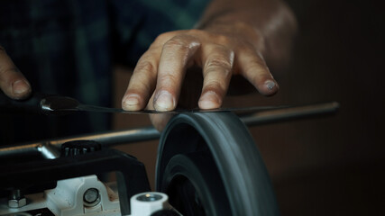Man sharpens knives on a grinder. Close up hand