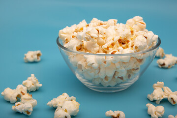 Glass bowl with popcorn on blue background