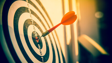 Bulls eye or dart board has red dart arrow throw hitting the center of a shooting target for...