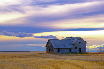 Abandoned farmhouse in rural alberta Canada with cloudy skies