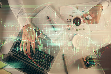 Multi exposure of man's hands typing over computer keyboard and forex graph hologram drawing. Top view. Financial markets concept.