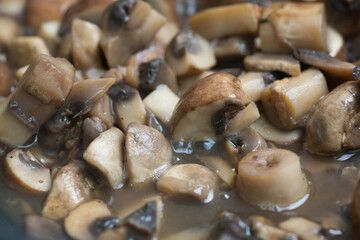Close up view of sauteed slices of Common Mushrooms (Agaricus bisporus) cooking in the pan