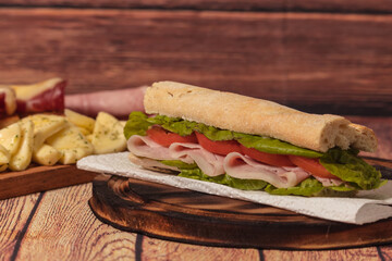 Ham, tomato and lettuce sandwich on a plate on a rustic background