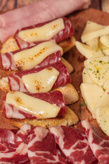 Tables of cold cuts - hams, bondiola -, cheeses and bruschetta tapas, Iberian ham and mozzarella.