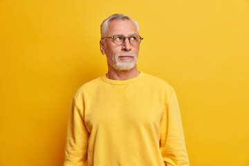 Wise intelligent bearded man concentrated away with thoughtful expression gazes determined on right...