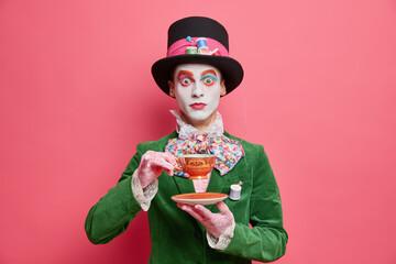 Surprised hatter drinks tea with aristocraic manners wears tall hat and green costume has image of...