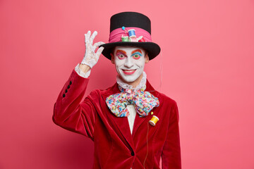 Positive mad hatter keeps hand on hat smiles happily takes part in carnival dresses for halloween...