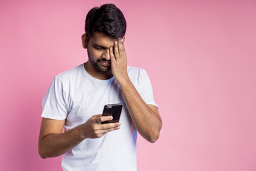 Portrait of handsome Indian guy standing on pink background