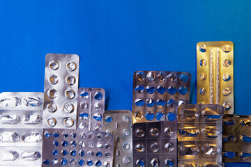 empty blister packs of pills in the form city on blue background.