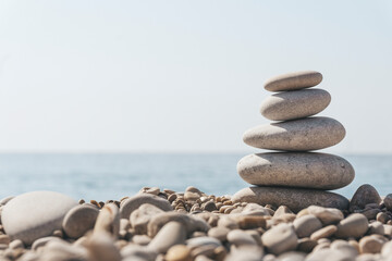 Fototapeta na wymiar Zen relax background. A pyramid of stones on the beach in clear sunny weather. Background for meditation, yoga and massage