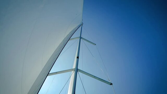 Mainsail And Mast Of A Sailboat Against Clear Blue Sky - low angle shot