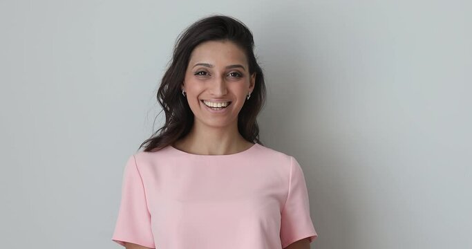 Head shot beautiful millennial smiling confident mixed race indian arabian woman looking at camera, showing healthy white toothy smile, feeling joyful, isolated on grey white studio background.