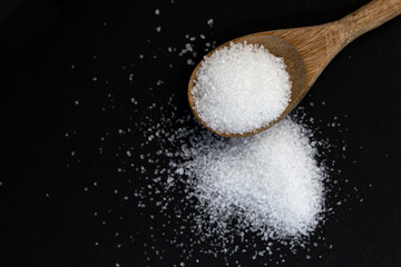 salt in wooden spoon on black background