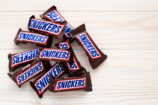 Kharkov, Ukraine, April 01, 2020: Heap of bars of snickers in wrapper on light wooden background. Illustrative editorial.