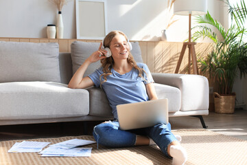 Image of pretty woman working with laptop while sitting on floor at home.