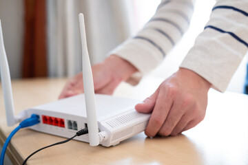 Men hands set up and install broadband high speed internet Wifi router on working table at home....