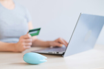 A faceless woman holds a credit card and a clitoral vibrator while sitting at a laptop. Online sex...
