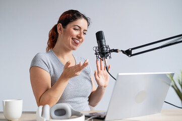A charming woman radio host is broadcasting live on a laptop. Online radio concept