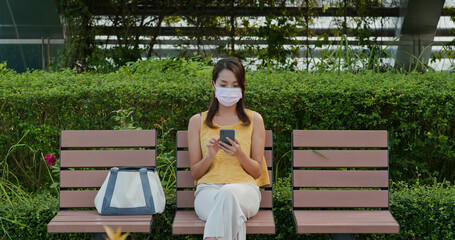 Woman wears face mask and uses mobile phone