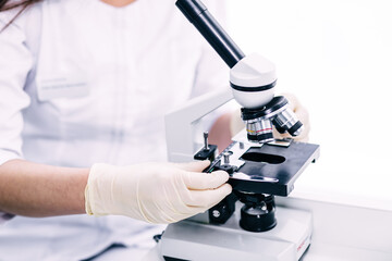 Young scientist looking through a microscope in a laboratory.