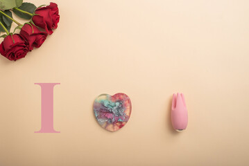 I love to masturbate. Rose heart and clitoral vibrator on a beige background. Flat lay