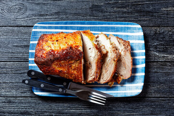 Oven-baked pork tenderloin on a plate with cutlery